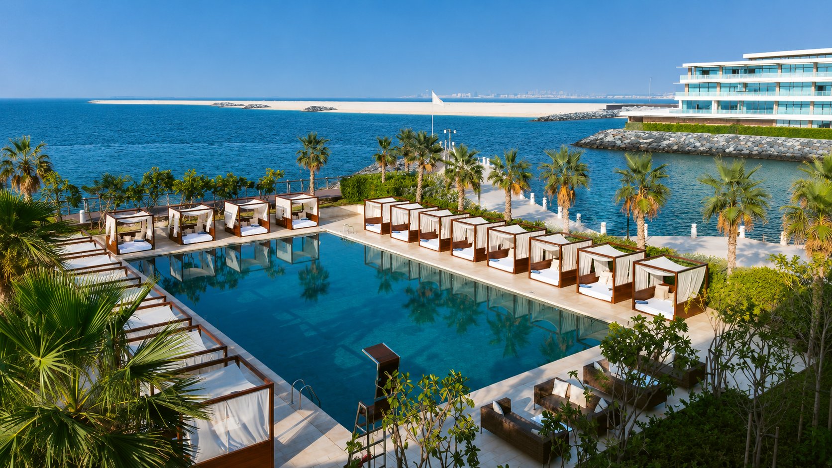 Bvlgari Resort Dubai luxury beach club with waterfront infinity pool, private cabanas, palm trees, and Arabian Gulf views on Jumeirah Bay Island.